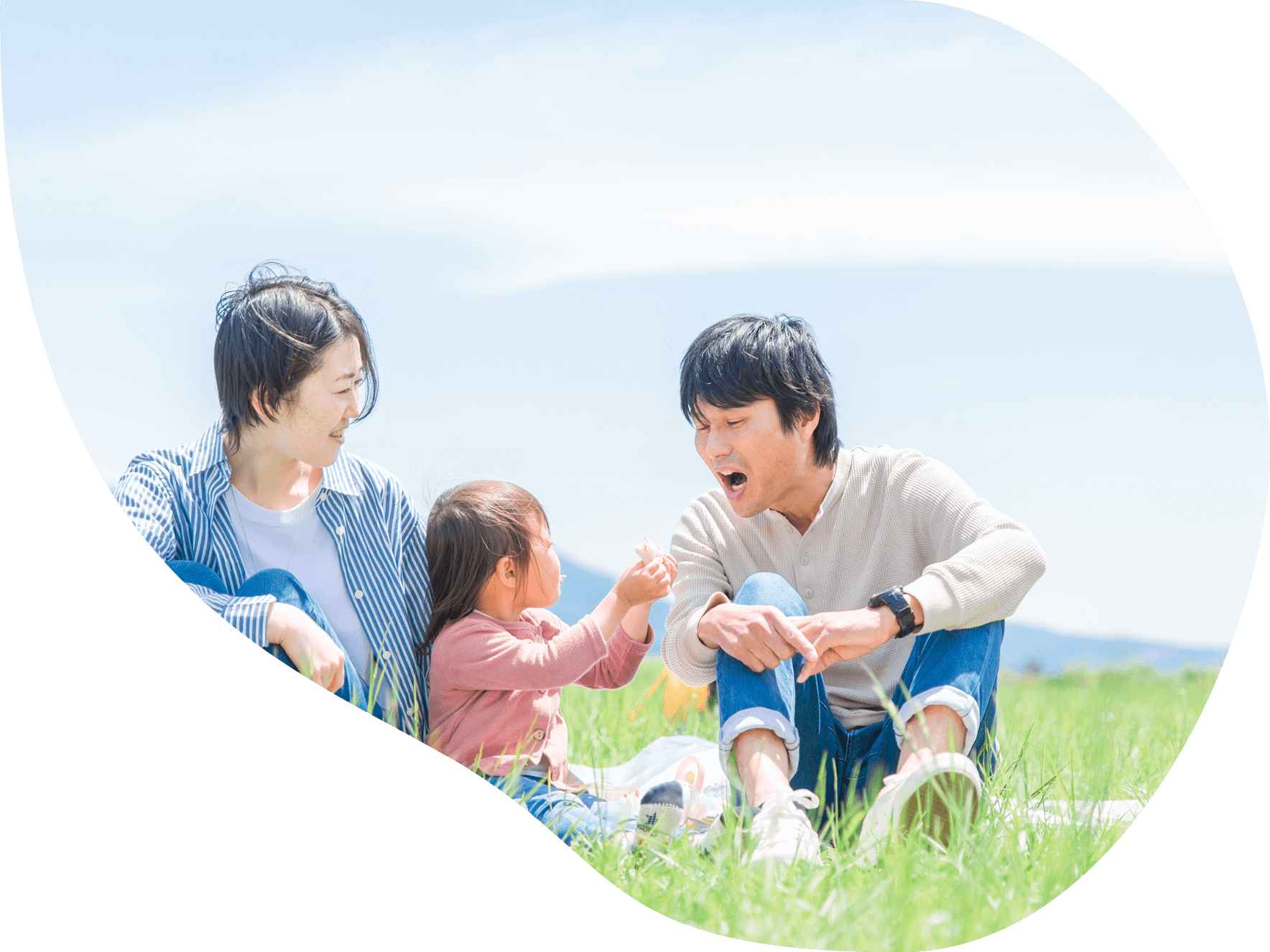 野原でサンドイッチを食べている親子